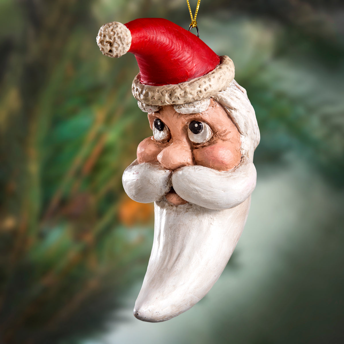 Bert Anderson crescent moon Santa ornament with red hat and long curved white beard displayed against a softly blurred green background.