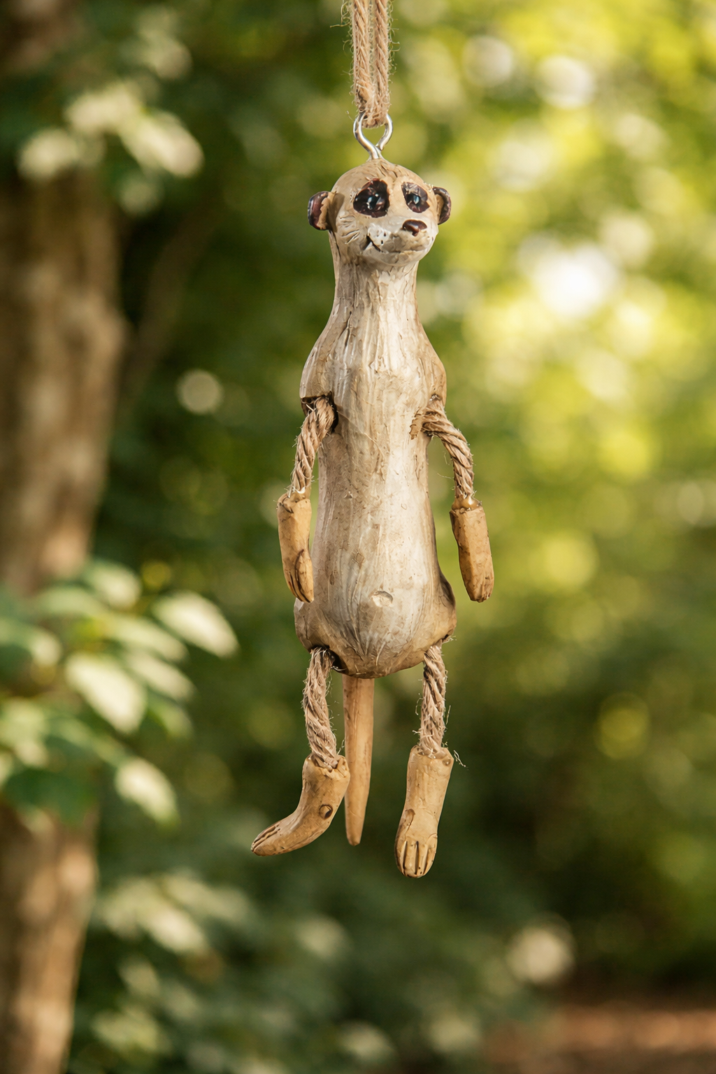 Meerkat hanging ornament on green foliage background.