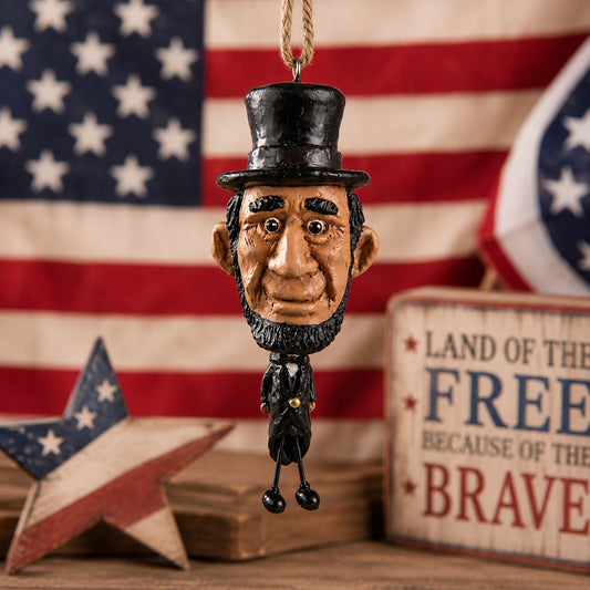 Abe Lincoln ornament with stovepipe hat and dangling wire legs displayed against an American flag and patriotic décor.