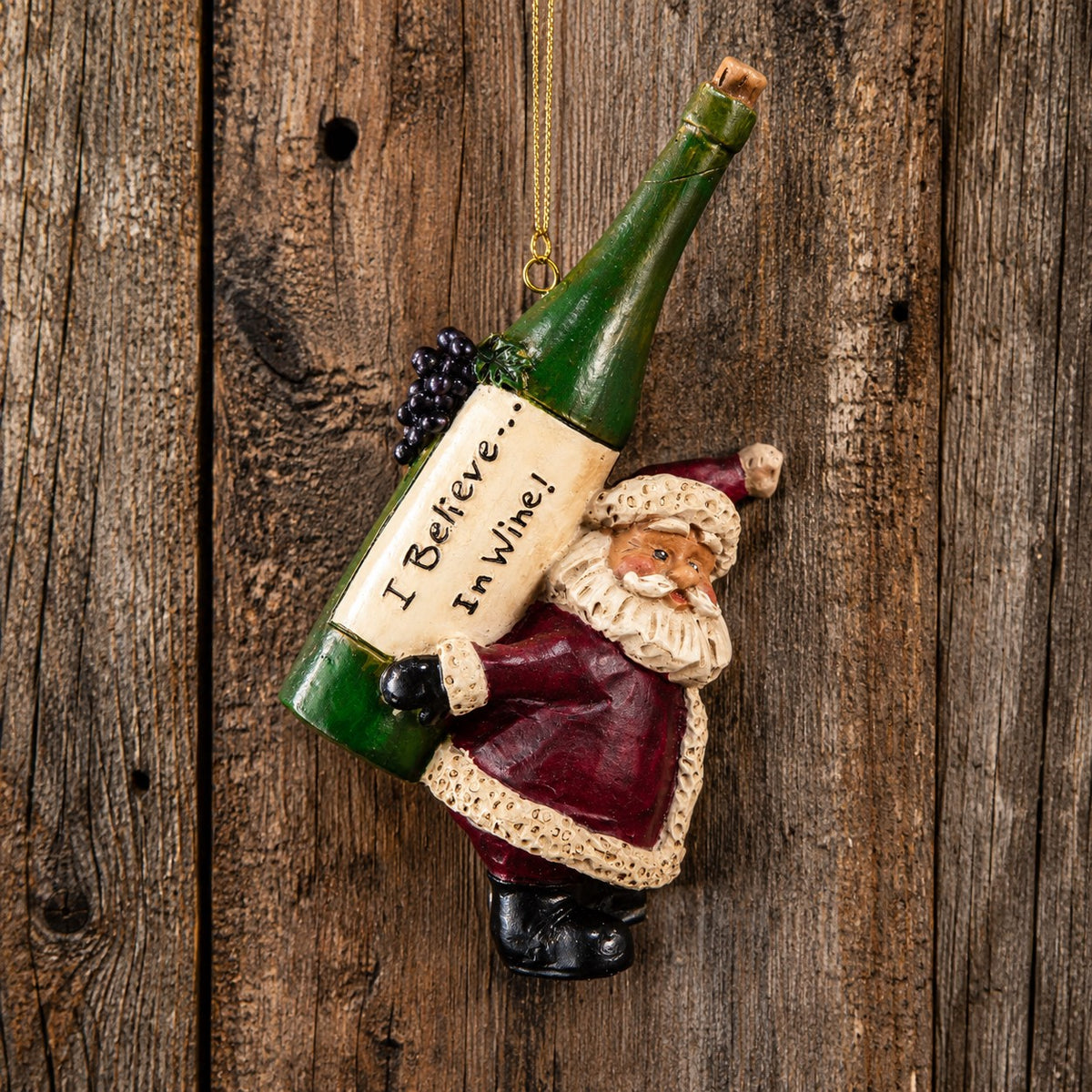 Bert Anderson Santa wine ornament carrying an oversized green bottle labeled “I Believe in Wine” against rustic barnwood.