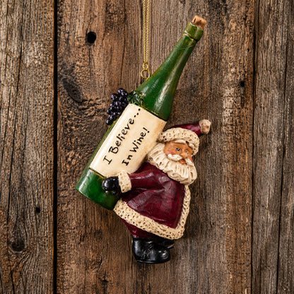 Bert Anderson Santa wine ornament carrying an oversized green bottle labeled “I Believe in Wine” against rustic barnwood.