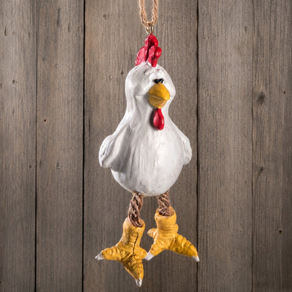 A hanging chicken ornament with a white body, red comb and wattle, yellow beak and feet, and brown rope legs, shown against a rustic wooden plank background. Cute farm animal.