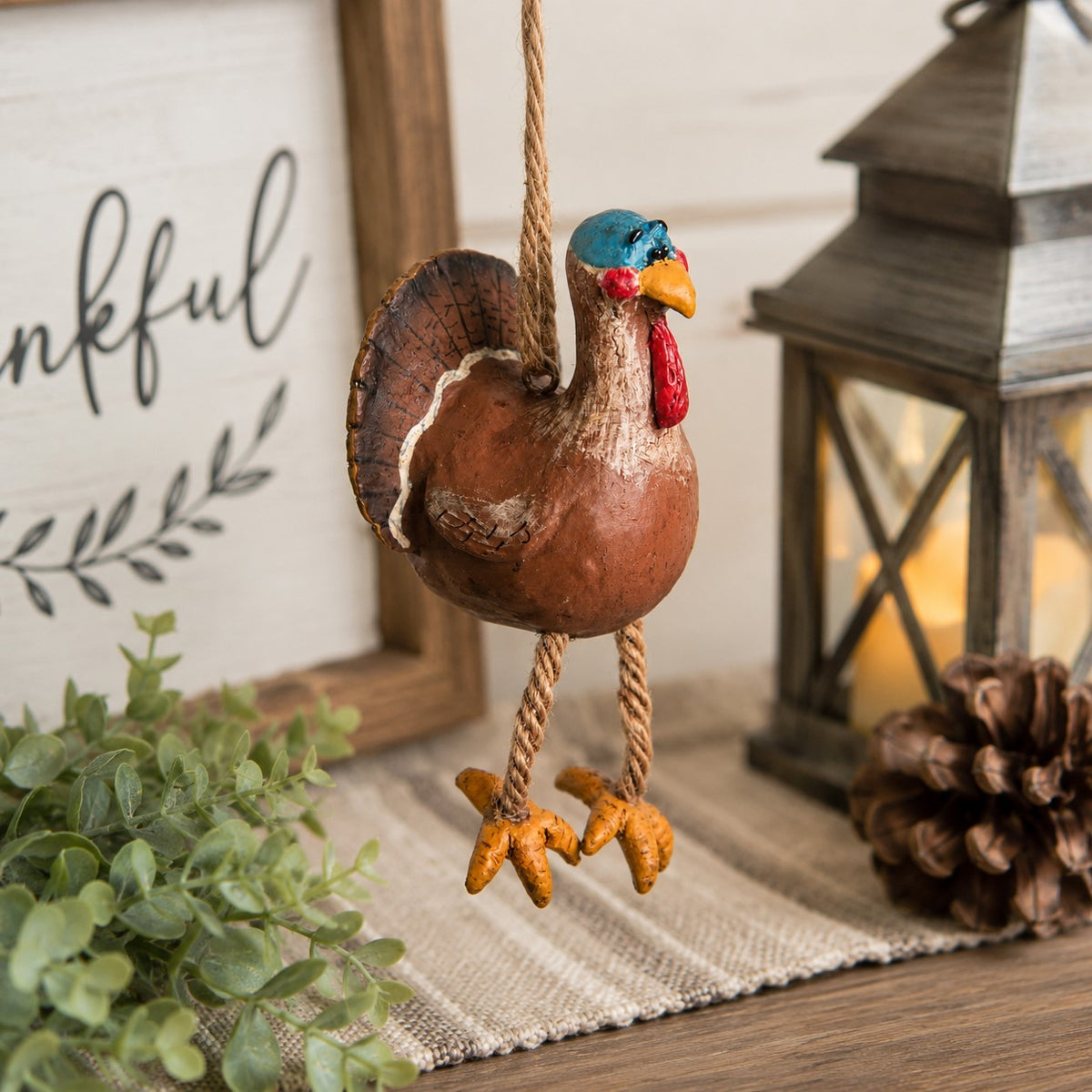 A rustic hanging turkey ornament made  with rope legs.  Colorful fun fall alnd Thanksgiving decor.