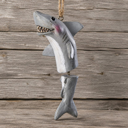 A shark hanging ornament with a gray and white body, open mouth showing teeth, and a natural jute hanging loop, photographed against a rustic wood plank background.