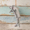 A hand painted dolphin hanging ornament with a natural twine loop at the top, shown against a distressed rustic wood plank background.