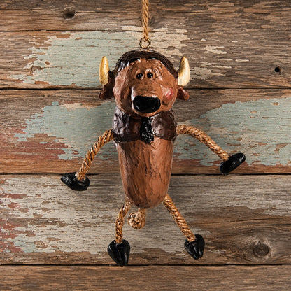 A rustic buffalo hanging ornament with rope legs and black hooves, displayed against a weathered wood plank background.