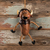 A rustic buffalo hanging ornament with rope legs and black hooves, displayed against a weathered wood plank background.