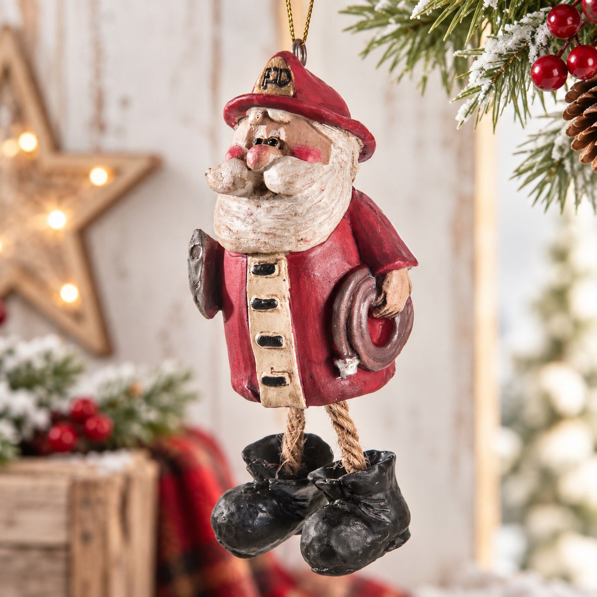 Bert Anderson firefighter Santa ornament with red fire helmet, hose, dangling rope legs and black boots in a bright Christmas setting.