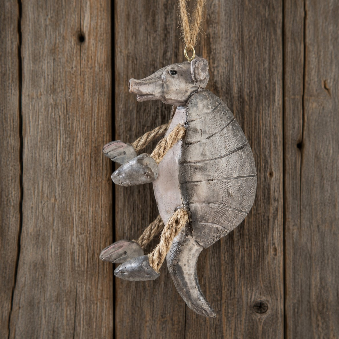 A rustic armadillo hanging ornament with a weathered gray finish and natural jute rope details.  Southwest Wildlife Decor.  