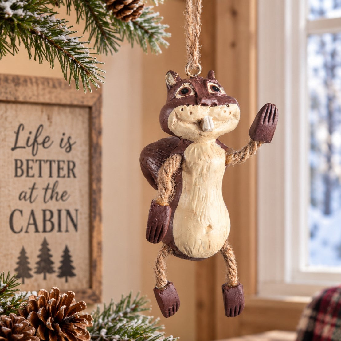Bert Anderson squirrel ornament with dangling arms and legs displayed in a light rustic cabin setting with a snowy window.