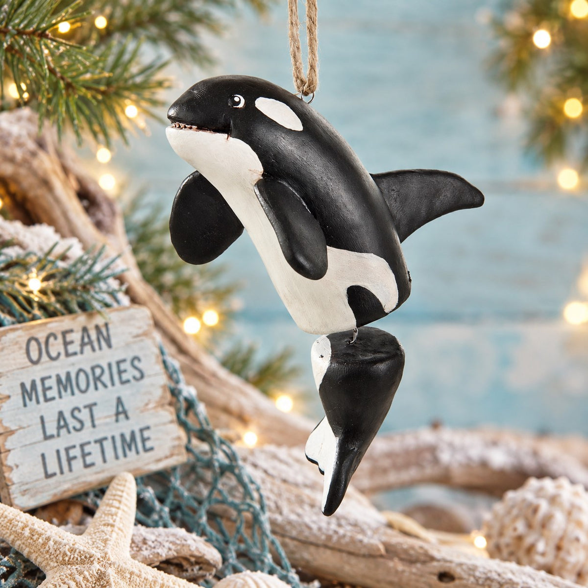 Bert Anderson orca killer whale ornament with dangling tail displayed in coastal décor with driftwood, starfish and warm lights.