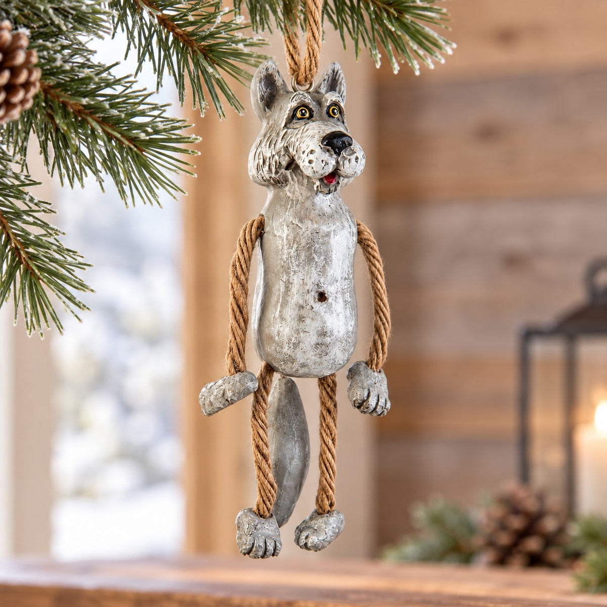 Bert Anderson wolf ornament with dangling rope arms and legs displayed in a bright rustic cabin setting with snowy window and simple winter greenery.