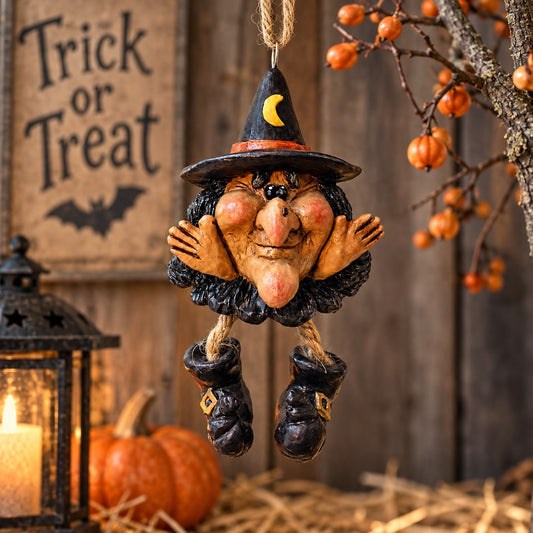 Bert Anderson witch ornament with dangling boots displayed in rustic Halloween décor with a pumpkin, lantern and orange berry branches.