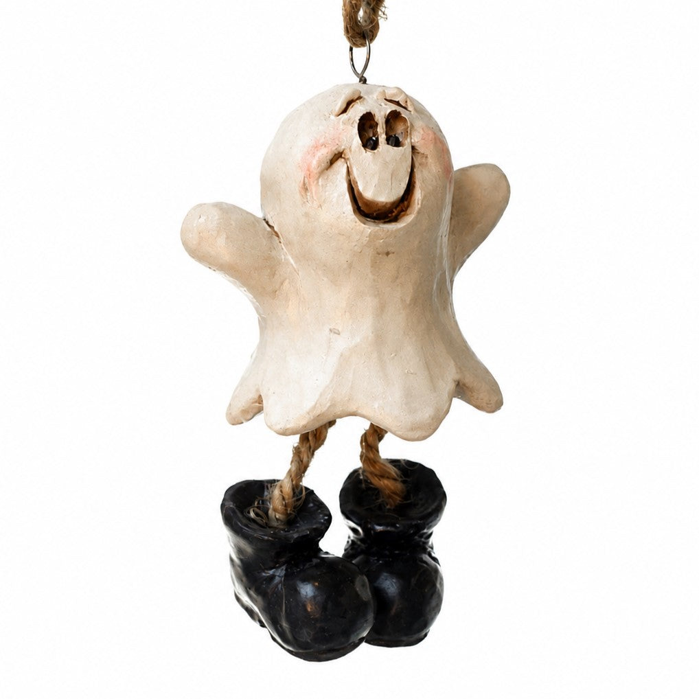 A whimsical Halloween ghost ornament with a distressed cream-colored body, a painted smiling face, and black boots, hanging from a jute rope on a white background.