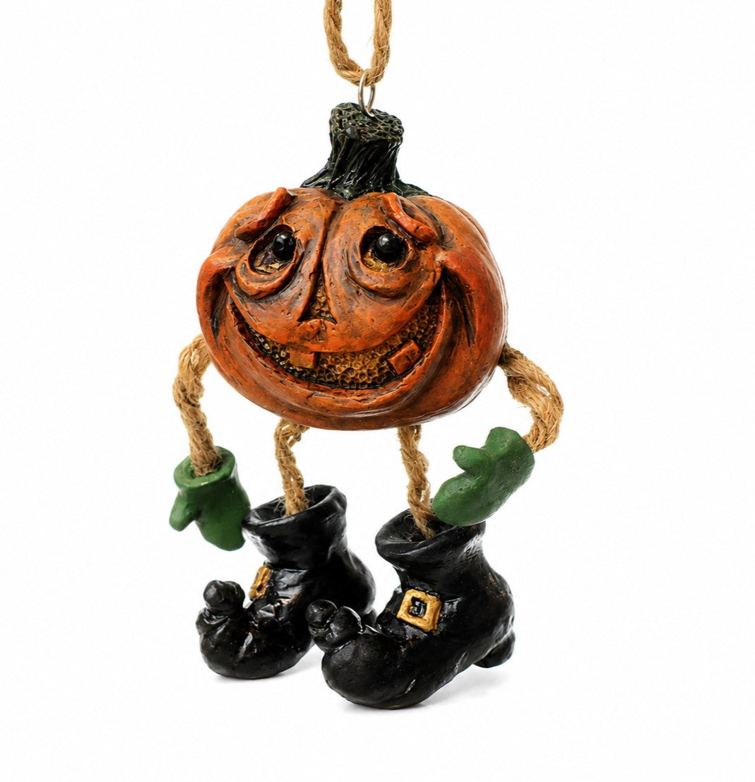 A Halloween hanging ornament shaped like a carved orange pumpkin with a smiling face, rope arms, green gloves, and black witch boots on a white background.

