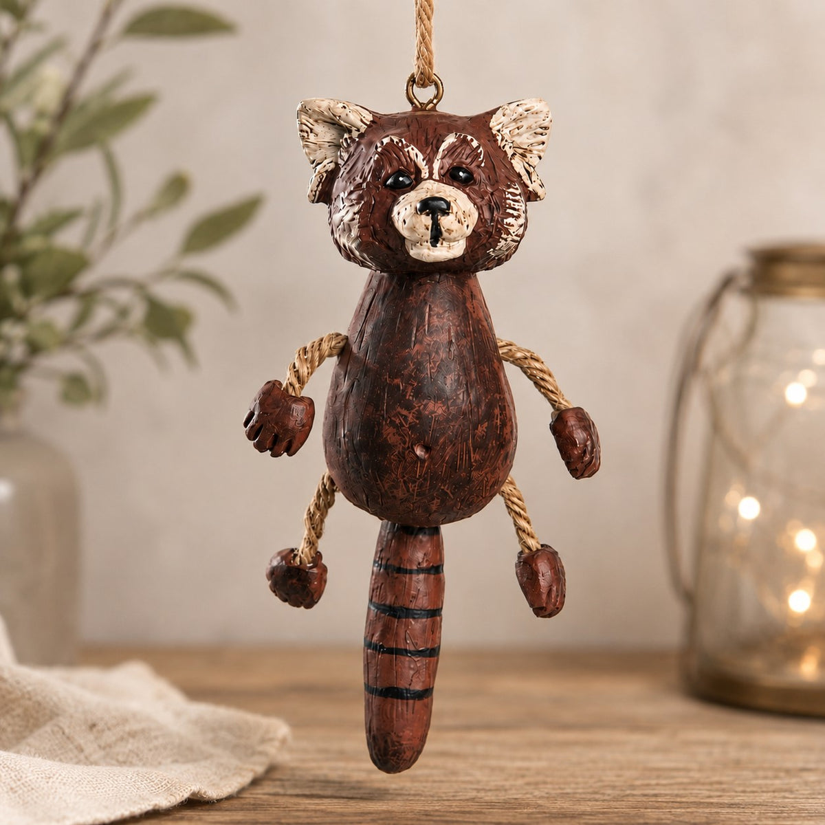 Whimsical red panda ornament with dangly rope arms and legs. Decorative home background.