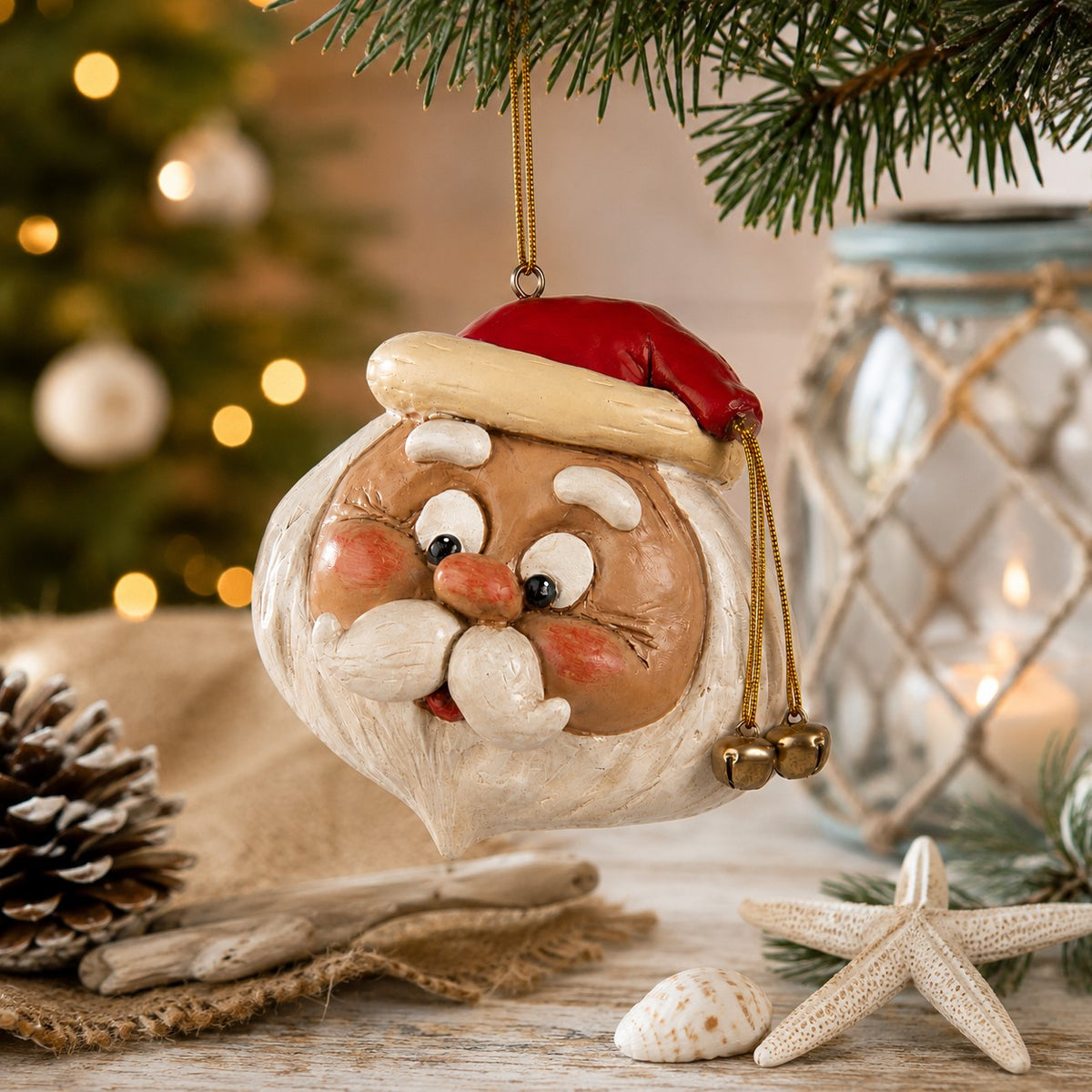 A festive Santa Claus Christmas ornament hanging from a pine branch, styled on a rustic tabletop with a blurred Christmas decor.