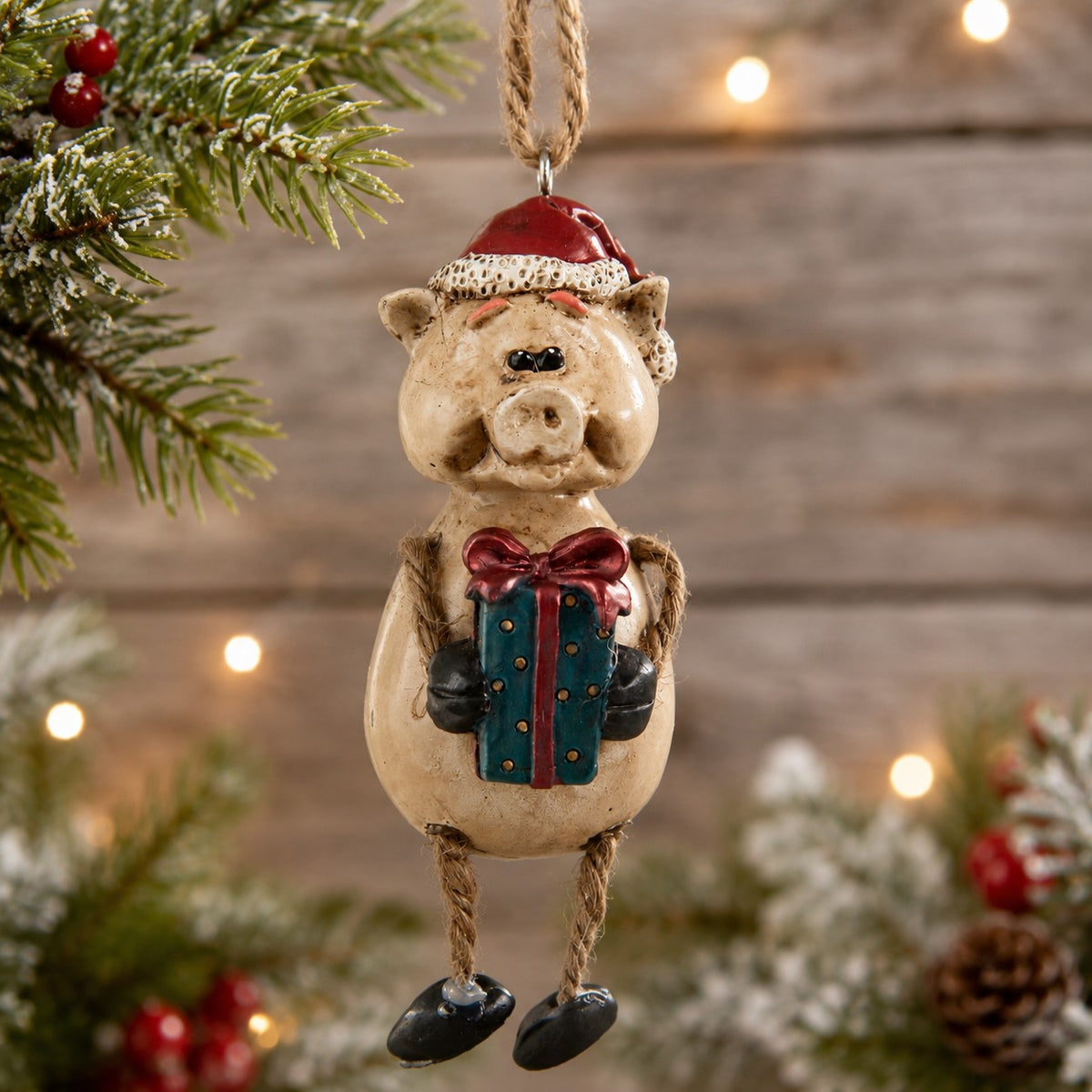 Christmas pig onrament with Santa hat and holding a present.  Features dangly arms and legs.
