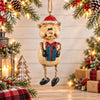 Bert Anderson pig Christmas ornament wearing a Santa hat and holding a wrapped present, displayed in a bright holiday setting with evergreen and warm lights.