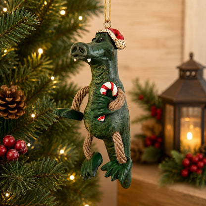Bert Anderson alligator Christmas ornament wearing a Santa hat and holding a candy cane with dangly rope arms and legs.