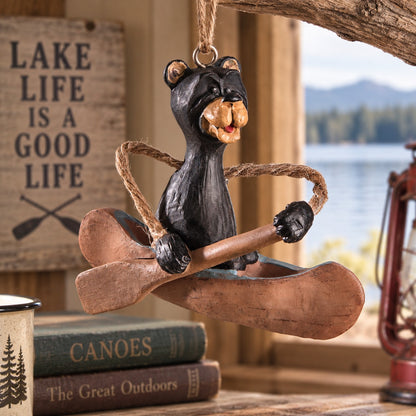 Bert Anderson bear in canoe ornament displayed in rustic lake house décor with a peaceful lake view in the background.