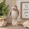 Bert Anderson manatee ornament with jointed tail hanging in a bright coastal home décor setting with seashells and greenery.