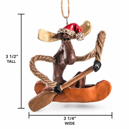 Bert Anderson moose in canoe Christmas ornament wearing a Santa hat with 3½-inch high and 3 1/4" wide measurement shown on a white background.
