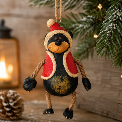 This rustic Santa Bear ornament  with his red hat and vest is hanging from a Christmas tree and cabin decor.