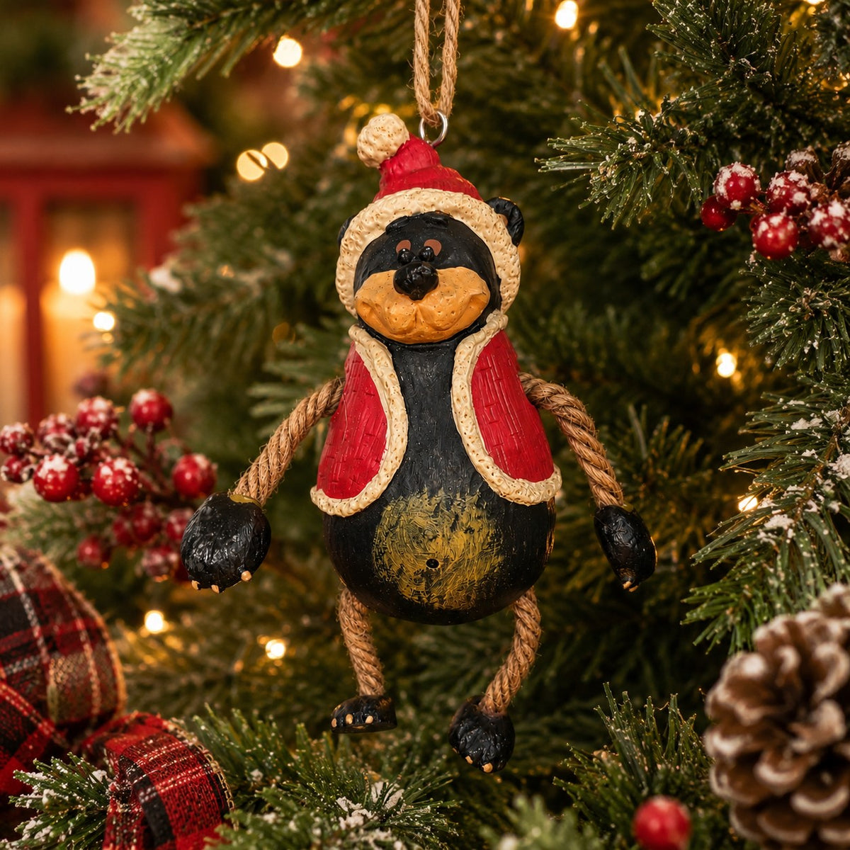 Santa Bear Ornament wearing a red hat and vest.  He has dangly arms and legs and is hanging on a Christmas tree.