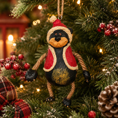 Santa Bear Ornament wearing a red hat and vest.  He has dangly arms and legs and is hanging on a Christmas tree.