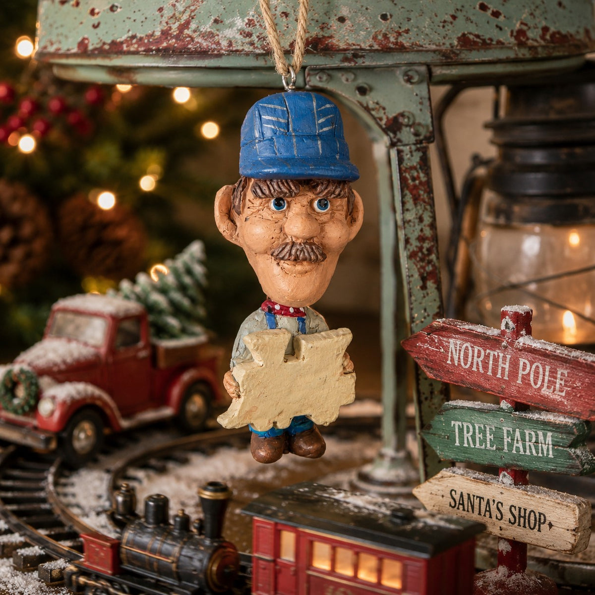 Bert Anderson train conductor ornament displayed in a nostalgic Christmas train setting with miniature locomotive, holiday greenery and vintage décor.