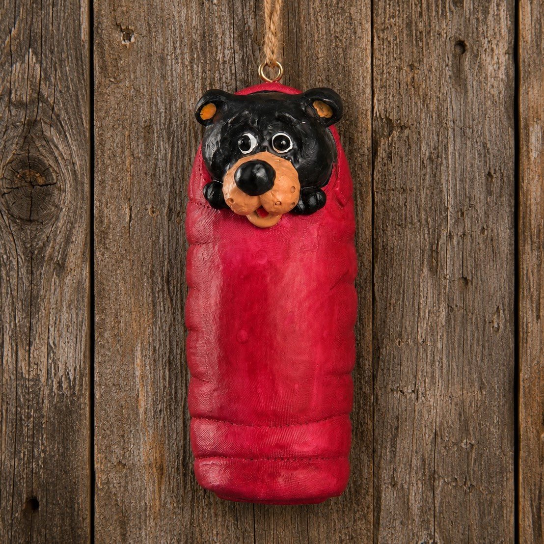Bert Anderson camping bear ornament hanging on a rustic wood background.