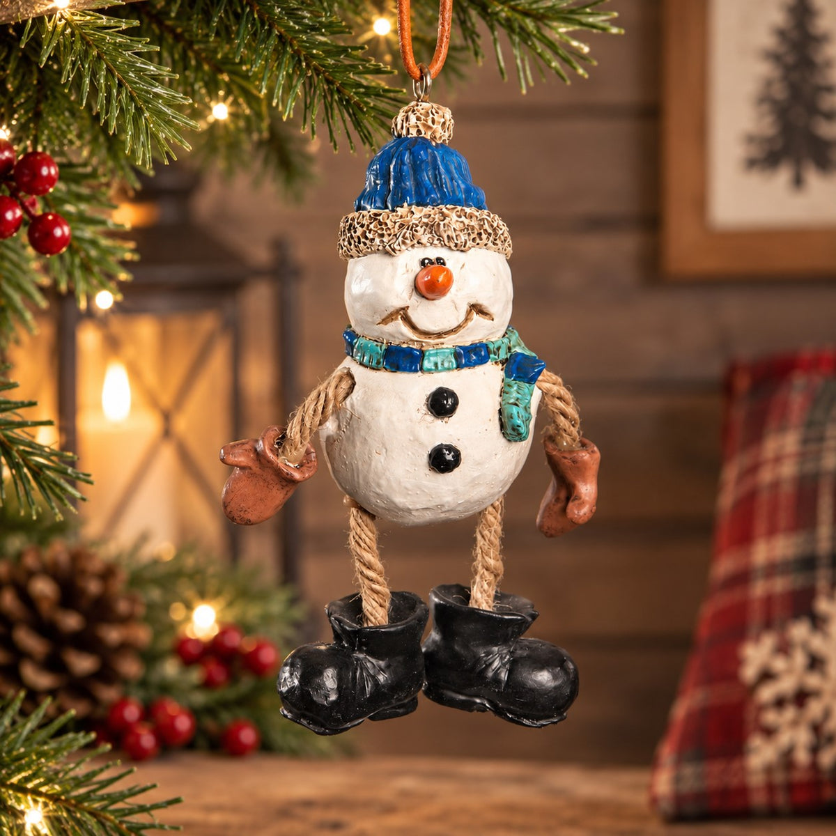 Dangly snowman ornament with blue hat and scarf, rope legs and black boots displayed in a cozy Christmas home décor setting.