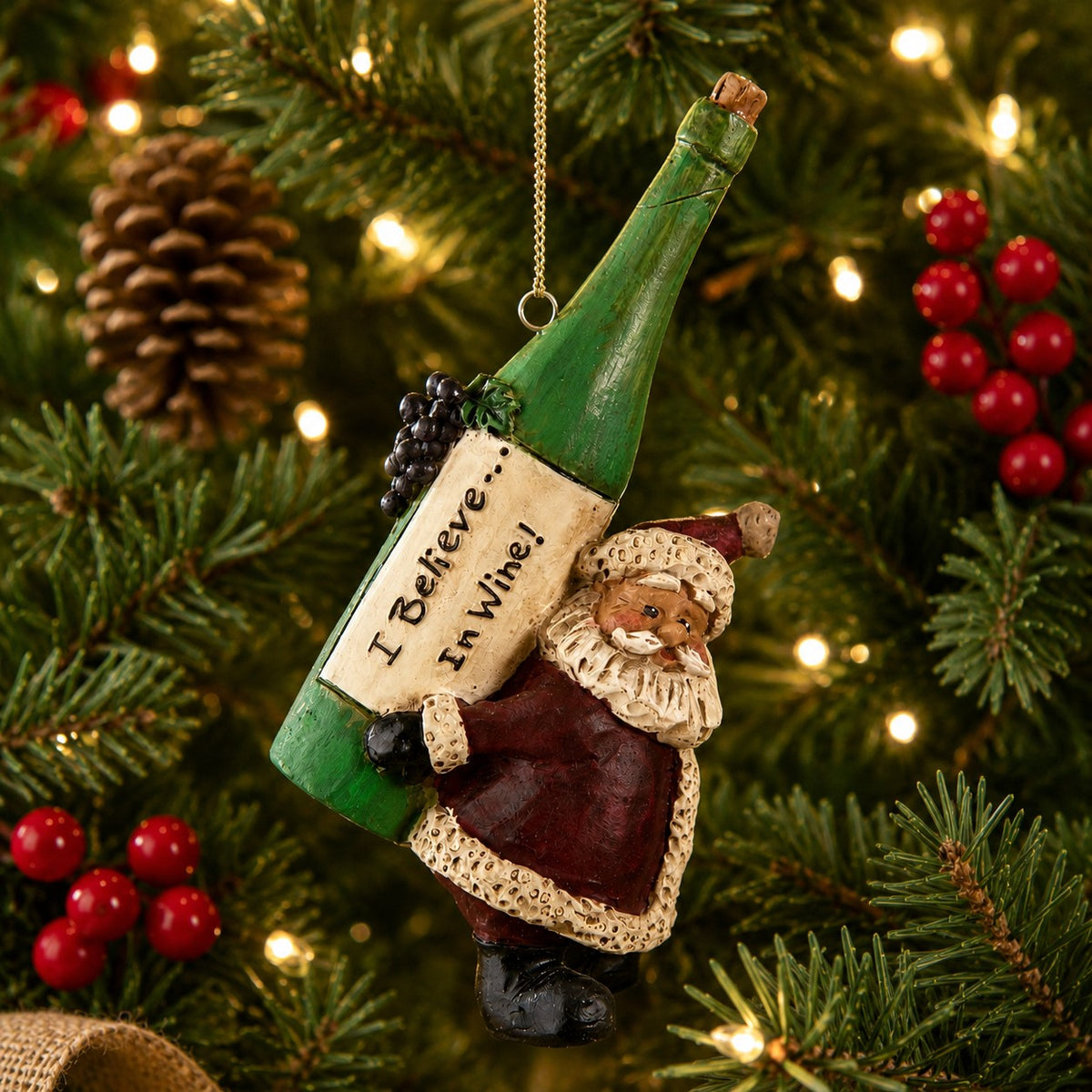 Bert Anderson Santa wine ornament with oversized wine bottle hanging on a Christmas tree with lights, pinecones and red berries.