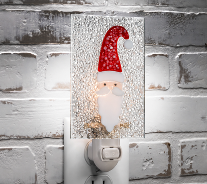 J. Devlin fused glass Santa Christmas night light illuminated against a white brick wall