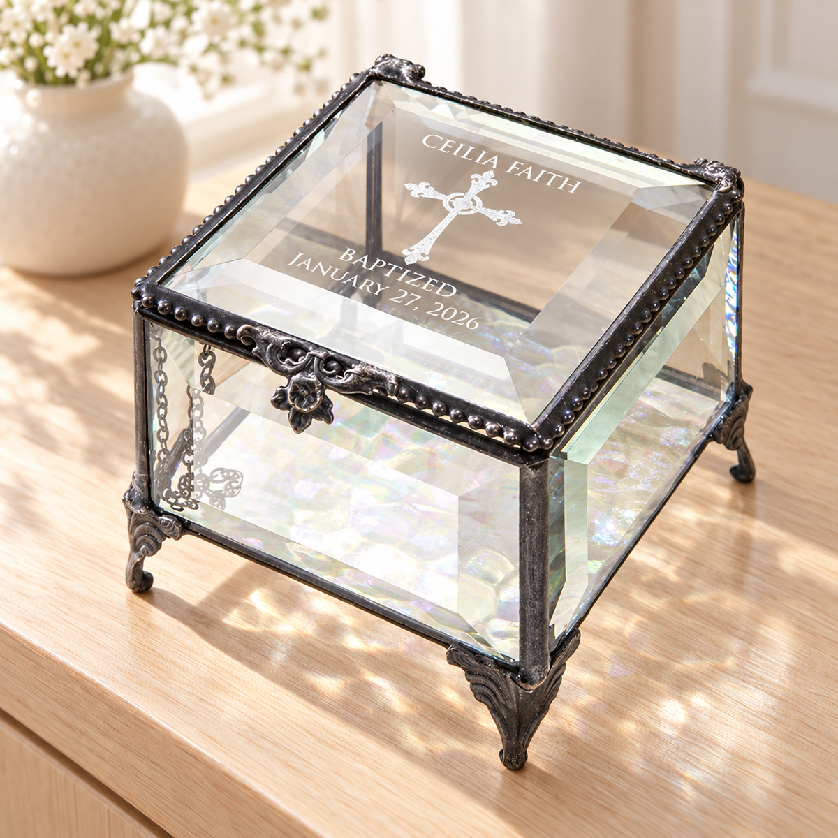 Clear beveled glass baptism keepsake box engraved Ceilia Faith, an ornate cross, Baptized and January 27, 2026, with decorative feet and iridescent bottom.