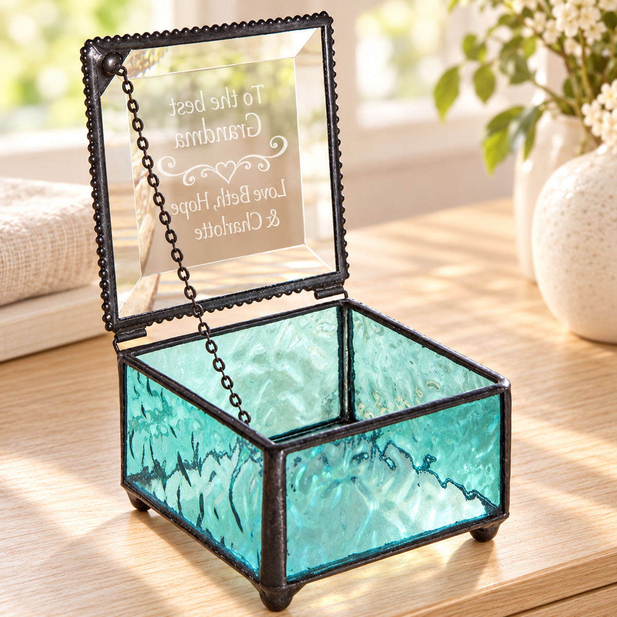 Open Windsor Blue glass Grandma keepsake box showing the clear beveled lid, support chain, iridescent interior, and heart-and-name engraving viewed from inside.